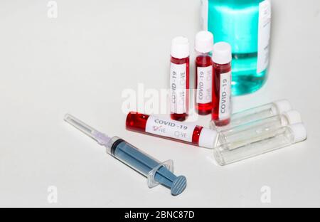 Injection syringe with blood test samples and empty vials on white table top for corona virus testing Stock Photo