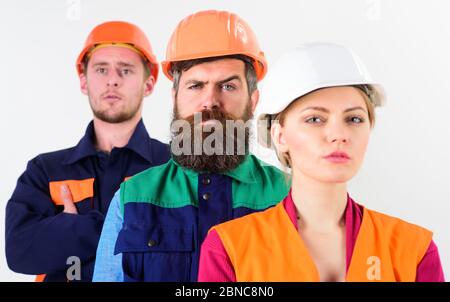 Serious team of three constructor workers in hard hats standing with arms folded isolated on white background Stock Photo