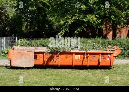 Orange dumpster with plant waste standing in a meadow, Germany, Europe Stock Photo