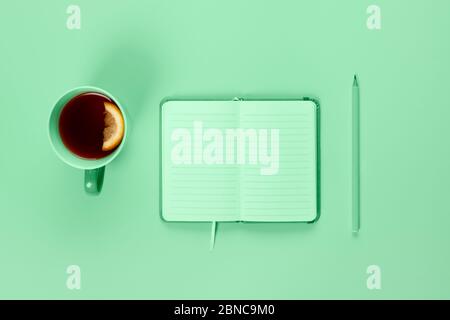 Tea cup and fancy notebook with empty or blank page on desk from above, planning and design concept. Top view, flat lay, copy space. Mock up toned in Stock Photo