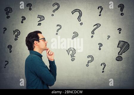 Businessman keeps hand under chin, thoughtful gesture, looking ahead focused, thinking answers to different questions in his head. Interrogation mark Stock Photo