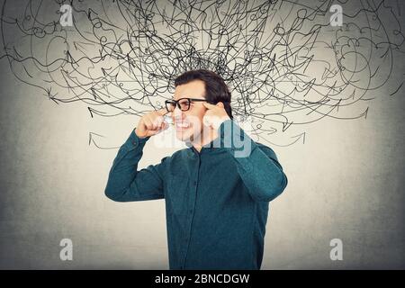 Annoyed irritated businessman, frowning and screaming due noise in head as mess arrows. Fatigue male suffers anxiety and headache.  Mental health prob Stock Photo