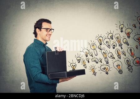 Businessman opens his briefcase filled with brilliant ideas as different lightbulbs comes out of the box. Ingenious boss shows the business portfolio, Stock Photo