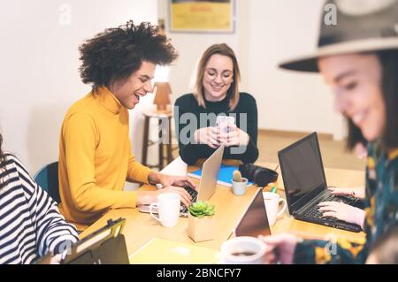 Happy young people working together inside office - Multiracial friends having fun collaborating in coworking space Stock Photo