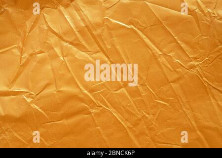 Gold paper texture top view. Crumpled paper yellow color background. Creases on packaging paper. Abstract texture of yellow wrinkled paper for Design, Stock Photo