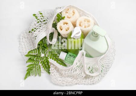 Different containers for lotion, shampoo, conditioner or liquid soap in eco bag. Loofah or luffa washcloth, vegetable sponge, alternative to plastic Stock Photo