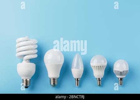 Energy-Saving light bulbs are arranged in a row on a blue background, top view. Progress of led lamps. Stock Photo