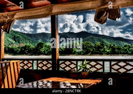 Beautiful view of Mekong River in Laos with a green mountain and cloudy sky in the background Stock Photo