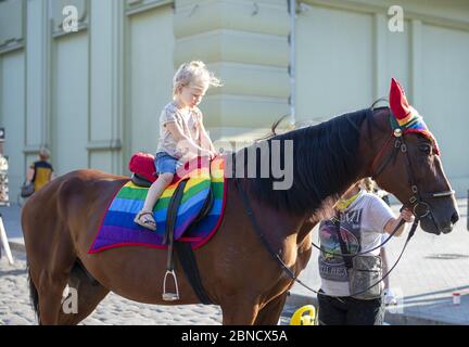 Odessa, Ukraine. July 22th 2018. Horse decked in pride colors. Horse riding - little girl is riding a horse. Stock Photo