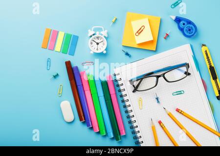 Office supplies are on the blue table, for working with your own hands at home. The color of the rainbow, pencils, glasses, Notepad and alarm clock re Stock Photo