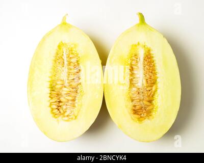 Two halves of a canary melon with seeds on a white background Stock Photo