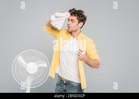Man with towel near electric fan isolated on grey Stock Photo