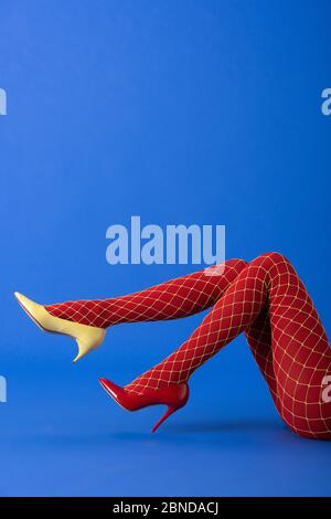 cropped view of model in fishnet tights and red heels posing on blue Stock  Photo - Alamy