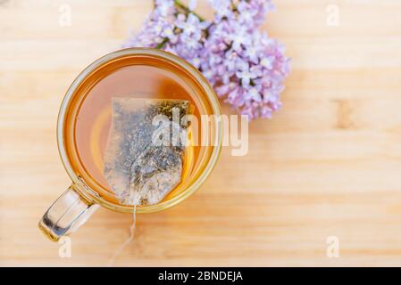 Hot beverage in glass mug on wooden table. Close-up herbal tea in bag tea, top view Stock Photo
