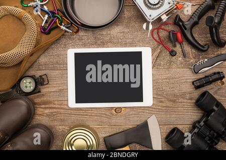 top view of digital tablet with black screen near hiking equipment on wooden table Stock Photo