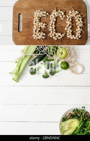 collage of eco word made of sprouts, green fruits and vegetables in string bag and bowl of microgreen and avocado on white wooden table Stock Photo