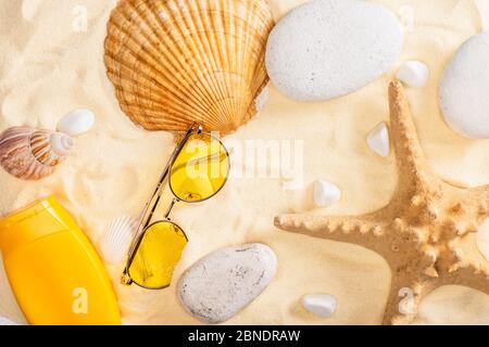 Top view of sunscreen and sunglasses near starfish and seashells on sand Stock Photo
