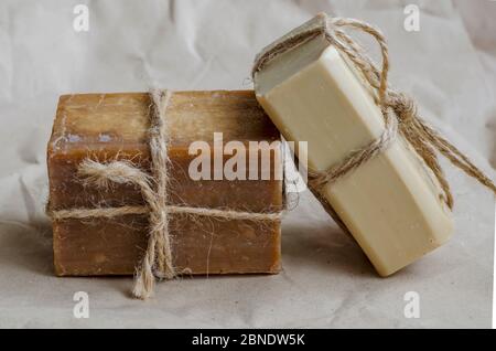 Pieces of laundry soap on a plain background. Two rectangular pieces of new soap wrapped with twine. Natural hygiene products. Place for text. Selecti Stock Photo