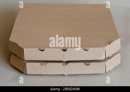 Cardboard boxes for pizza close-up. Two closed brown boxes in a stack. Food packaging and delivery. Courier service. Close-up. Selective focus. Stock Photo