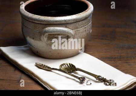 Vintage Pottery bowl with antique spoons on napkin on a wooden table Stock Photo