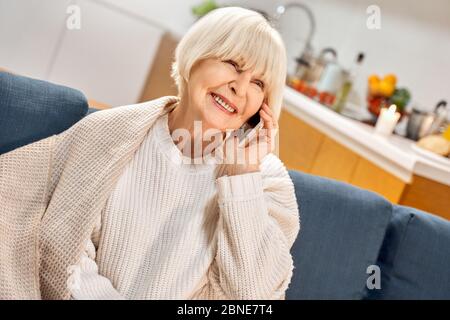 Senior woman using modern smartphone, resting at home Stock Photo