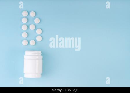 Vitamin B pills dropped from bottle on blue. Letter B inscription from tablets. Vitamin B12 concept. Immunity protection concept, antiviral prevention Stock Photo