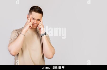Beautiful young man with a fashionable haircut, guy massaging whiskey with his fingers, trying to concentrate on work. Stock Photo