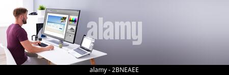 Designer Editing Photos On Multiple Computer Screens Stock Photo