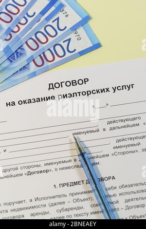 Registration of an agreement on a transaction with property. Russian text of the 'Contract of real estate services', ruble bills for payment and handl Stock Photo