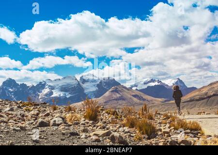 Woman walking on the Andean mountain range trail to the Pastoruri glacier, in the Huascarán National Park, Huaraz / Peru. Tropical glacier at 5200 met Stock Photo