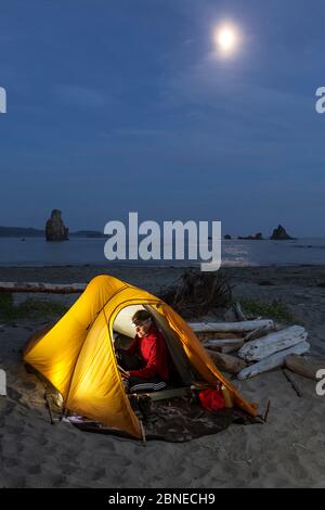 Moon rising over campsite, Toleak Point, Olympic National Park, Washington, USA. August 2015. Model released. Stock Photo