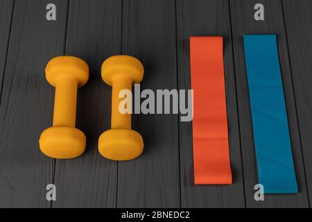 Multi-colored rubber bands for fitness and dumbbells isolated on grey background Stock Photo