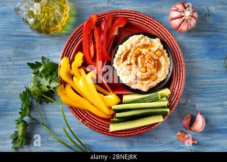 Close up of bright and colorful red platter of assorted fresh vegetables with hummus dip Stock Photo