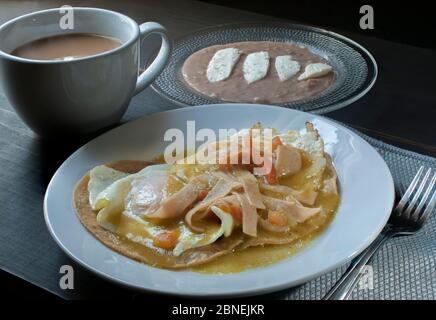 Side view of huevos rancheros or ranch eggs with fried beans, goat cheese, and milk coffee, Mexican breakfast concept Stock Photo