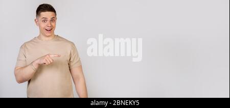 Handsome strong young man pointing finger to the right with a surprised expression on his face. Copy ad space Stock Photo