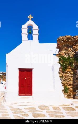 Old street with white ancient greek church in Mykonos town (Chora), Greece Stock Photo