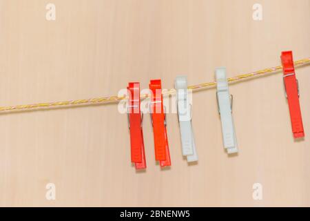 Pink clothespins on a wicker rope. Plastic clothespins for drying clothes. Stock Photo