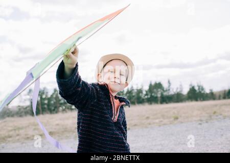 young boy holding a kite smiling whilst outside on a sunny day Stock Photo