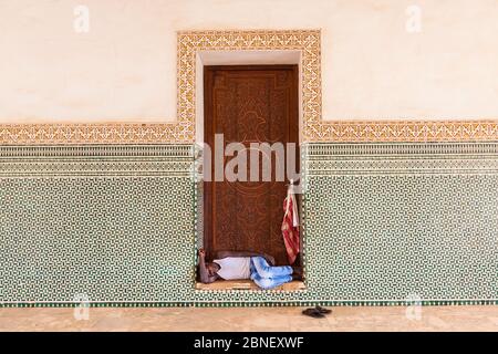 Homeless man sleeping in a doorway. grand mosque beautiful ornament wooden door Stock Photo