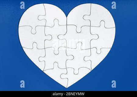 Jigsaw puzzle pieces in form of heart on blue background. Love, charity, donation, helping concept. Perfect match, reunion. Stock Photo