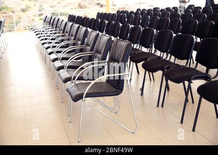 Uniqueness concept. Rows of black folding chairs empty in a conference room . Unique throne or ceremonial armchair with seat and golden details among Stock Photo