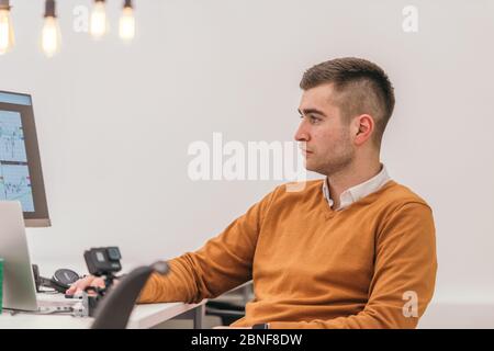 A casually dressed employee performing daily activities while working on a pc. Stock Photo