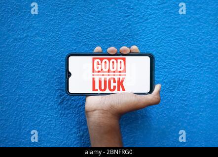 Good luck wording on smart phone screen isolated on blue background with copy space for text. Person holding mobile on his hand and showing front of t Stock Photo