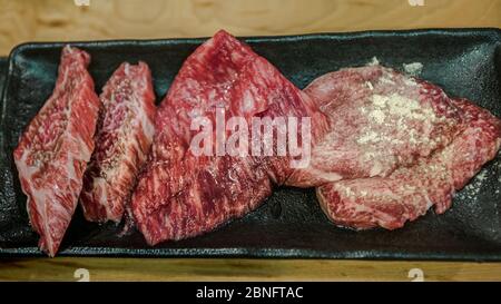 Thinly sliced Japanese wagyu beef on grille for barbecue. Grill one of the best beef in Japan. Style Yakiniku meaning grilled meat cuisine. BBQ food. Stock Photo