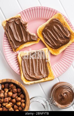 Toast bread with hazelnut spread on pink plate. Sweet chocolate cream. Top view. Stock Photo