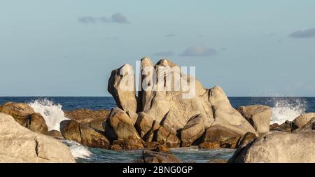 Huge rock on a beach in Aruba with water splashing around it Stock Photo
