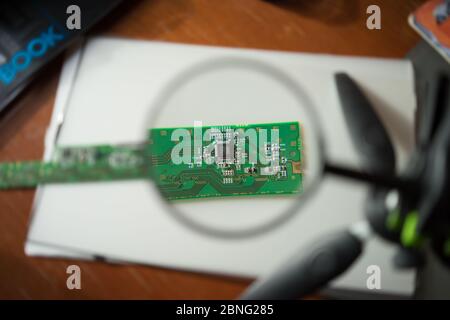 Engineer looking at a circuit board through a magnifying glass Stock Photo