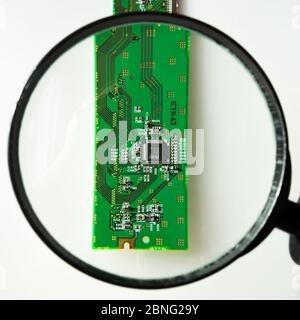 Engineer looking at a circuit board through a magnifying glass Stock Photo