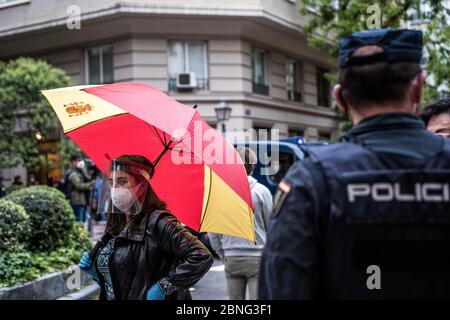 A woman wearing a face shield as a preventive measure holds an umbrella as she takes part during the demonstration The residents of the upscale Salamanca neighbourhood protest against the government's management of the coronavirus crisis. Some parts of Spain have entered 'Phase One' transition since their coronavirus blockade, allowing many stores to reopen, as well as restaurants serving outdoor customers but the places most affected by the Covid-19, such as Madrid and Barcelona, remain in a stricter 'Phase 0' quarantine. Stock Photo