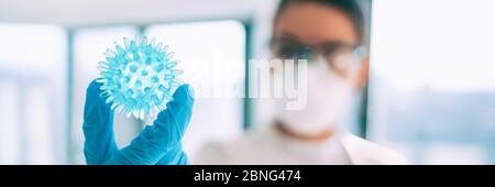 COVID-19 vaccine research worker looking at coronavirus in lab looking for a cure banner panoramic background . Asian woman scientist wearing PPE gloves, mask and goggles. Stock Photo